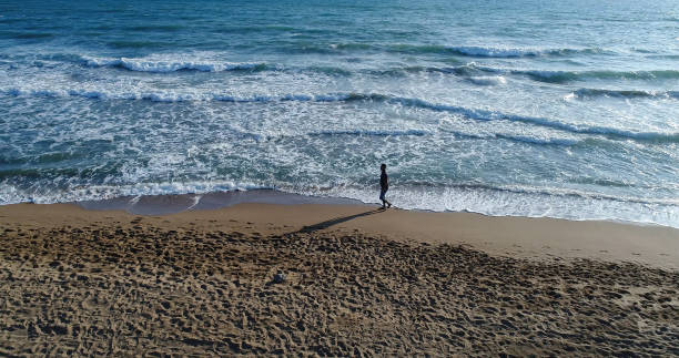 istock High angle view of man walking on the beach 859798348