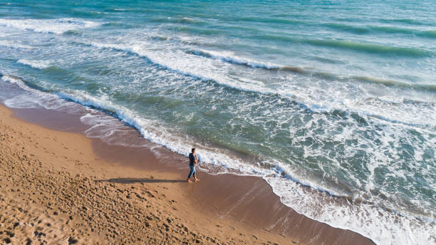 istock High angle view of man walking on the beach 859798926