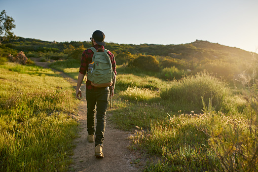 male millennial hiker walking trail in california during sunset in california