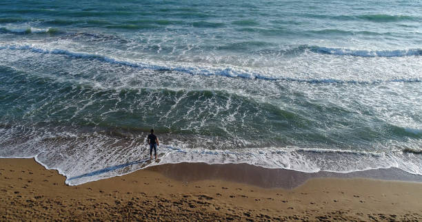 istock High angle view of man standing on the beach 859803228