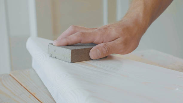 Close-up of male hands polishing wooden step with sandpaper stock photo
