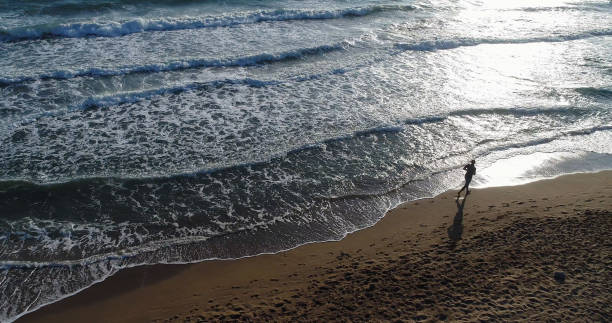 istock High angle view of man jogging on the beach 859804006