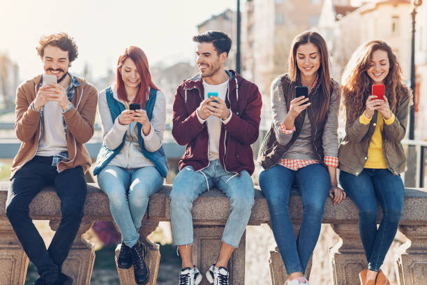 redes sociales en la ciudad - adicto grupo de jóvenes amigos usando teléfonos móviles fotografías e imágenes de stock