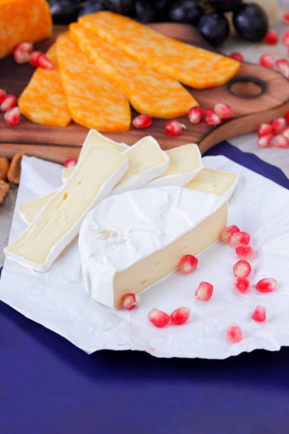 istock Camembert cheese, marbled cheese, different cheeses, dark blue grapes, red pomegranate, green grapes, peanuts and walnuts on a wooden board with an empty place for writing 859807218