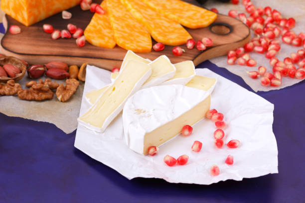 istock Camembert cheese, marbled cheese, different cheeses, dark blue grapes, red pomegranate, green grapes, peanuts and walnuts on a wooden board with an empty place for writing 859807322