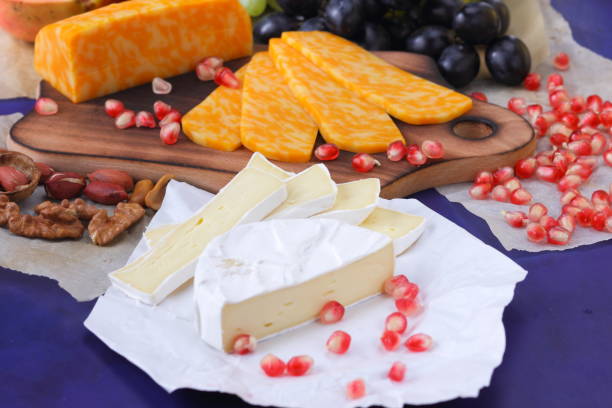istock Camembert cheese, marbled cheese, different cheeses, dark blue grapes, red pomegranate, green grapes, peanuts and walnuts on a wooden board with an empty place for writing 859807392