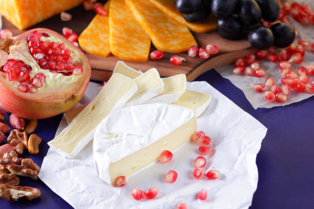 istock Camembert cheese, marbled cheese, different cheeses, dark blue grapes, red pomegranate, green grapes, peanuts and walnuts on a wooden board with an empty place for writing 859807880