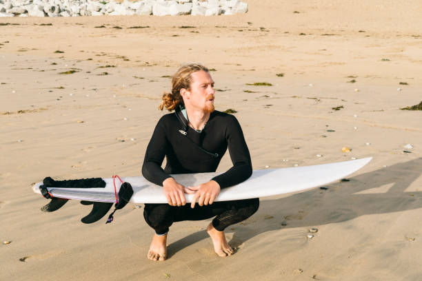 istock Surfer kneeling with his surfboard on Fistral Beach, Newquay, Cornwall. 859816444