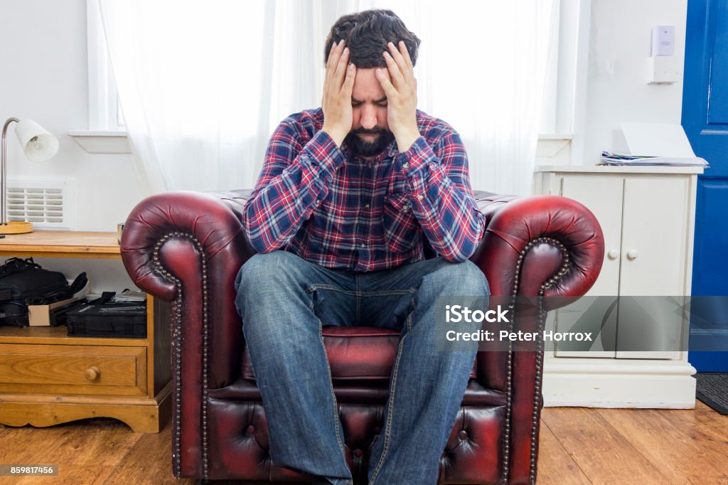 White man sitting in red chair with his head in his hands 30-39 Years Stock Photo