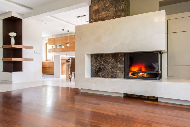 Marble fireplace in a vast living room with panelled floor, joined with bright kitchen