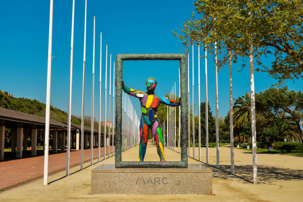 Barcelona, Spain - April  10, 2017: Sculpture Marc in front of the 169 flag posts of the nations that sent athletes to the 1992 Summer Olympics in Barcelona. The Park of Olympic volunteers