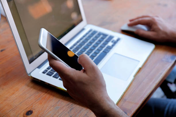 istock Male hand using mobile phone with laptop 859829988