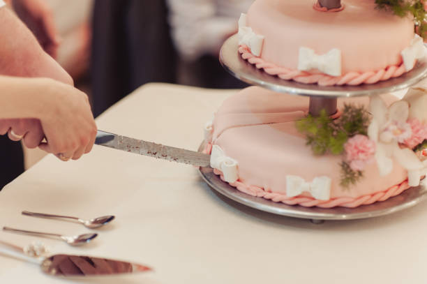 istock Beautiful white and colored wedding cake. A bride and a groom is cutting their wedding cake 859837400