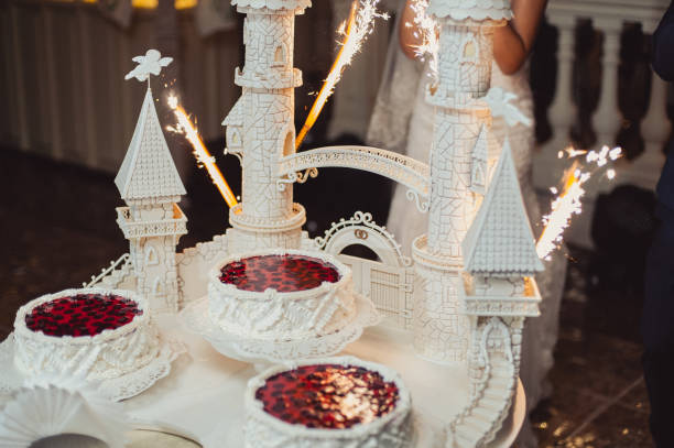 istock Beautiful white and colored wedding cake. A bride and a groom is cutting their wedding cake 859838408