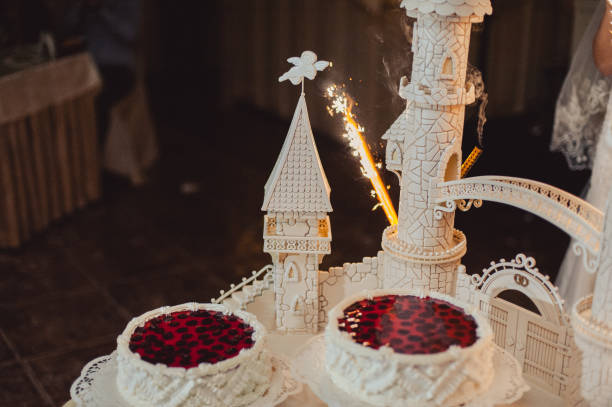 Beautiful white and colored wedding cake. A bride and a groom is cutting their wedding cake