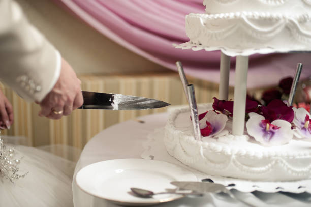 istock Beautiful white and colored wedding cake. A bride and a groom is cutting their wedding cake 859849414