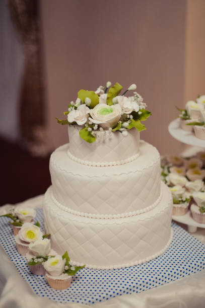 istock Beautiful white and colored wedding cake. A bride and a groom is cutting their wedding cake 859851784