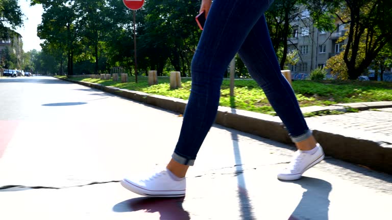 Video footage of the legs of one female crossing the street. Anonymous footage.