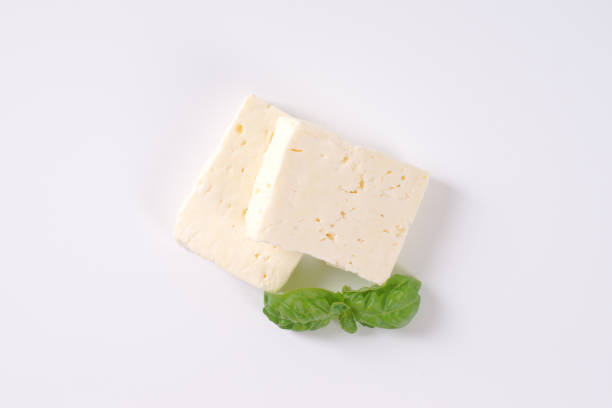 fresh feta cheese two pieces of fresh feta cheese with basil on white background feta cheese block stock pictures, royalty-free photos & images