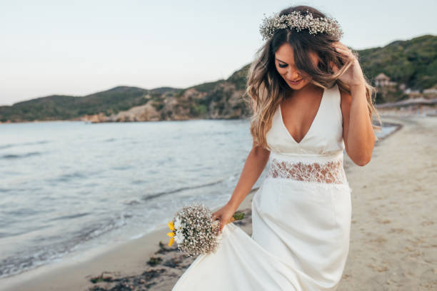 sposa che cammina sulla spiaggia - wedding dress bouquet wedding bride foto e immagini stock