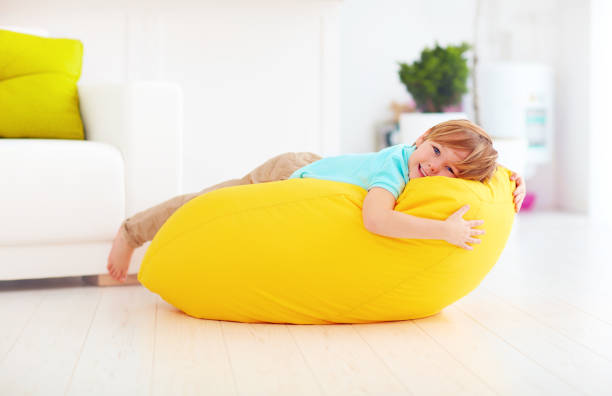 istock happy kid having fun on yellow bean bag at home 859875784