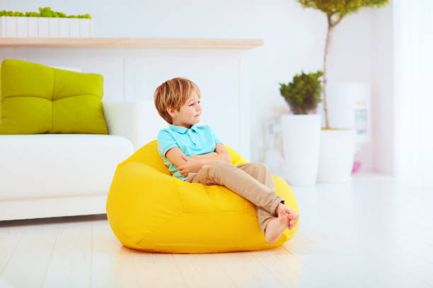 istock cute kid having sitting on yellow bean bag at home 859875956