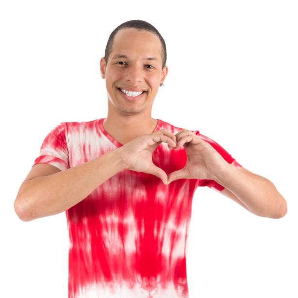 romantic man is making a heart gesture with his hand. he is charming. young latin american man wearing white and red shirt. white background. - stripped shirt imagens e fotografias de stock