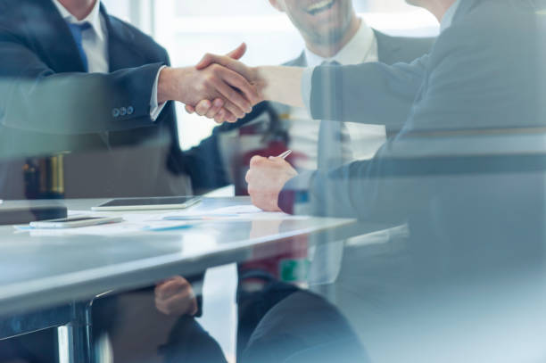Businessmen shaking hands at the board room table.