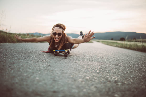One woman, riding her skateboard on the street far from the city, in nature.