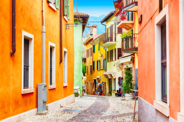 ciudad pequeña estrecha vista a la calle con casas de colores en malcesine, italia durante el día soleado. lago de garda. - narrow alley fotografías e imágenes de stock