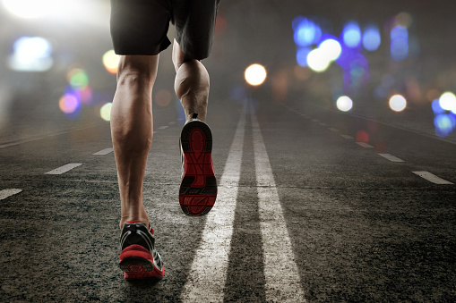 Runner crosses the finish line on a red treadmill with the numbers 2023. New year entry concept, step