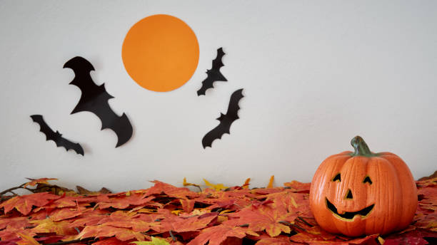 istock Happy Halloween pumpkin head jack lantern with bat and moon on leaves 859933354