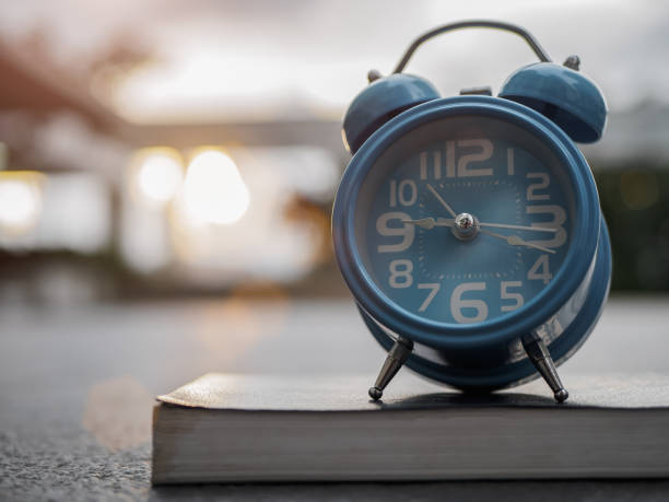 istock Closeup alarm clock on book with sunset background. 859933890
