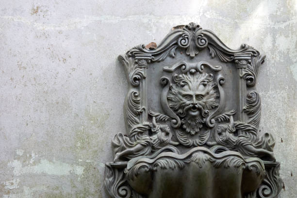 istock Old Lion Head Fountain, which is mounted on a white-gray wall. Which is not used for a long time, do leaves covered. See the whole garden. copy space 859936708