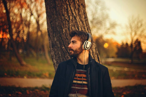 istock Bearded man leaning on tree in a park at sunset 859956320
