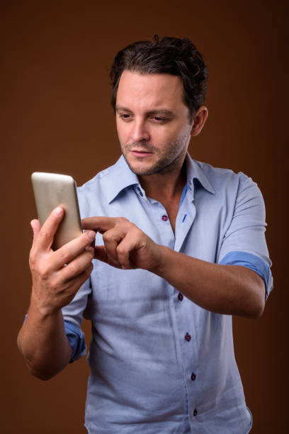 istock Studio shot of Italian businessman using mobile phone against colored background 859959064