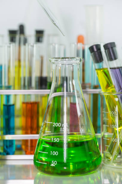 istock Pipette dropping over the green chemical solution in Erlenmeyer flask and test tubes with colorful chemical solution in test tubes rack on the table 859959968