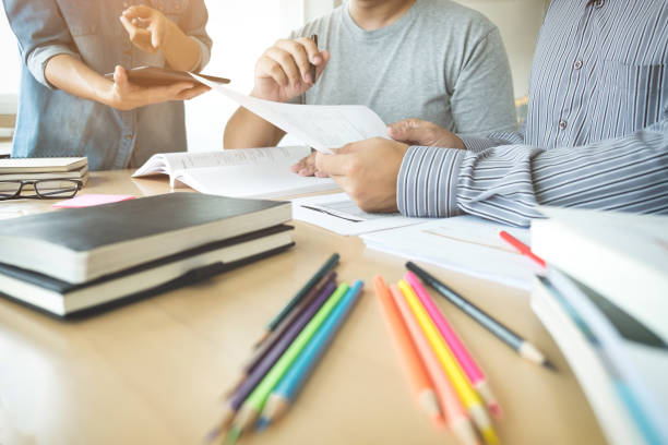 istock Education, teaching, learning, technology and people concept. Group of high school students or classmates with helps friend catching up workbook learning in classroom, Tutor books with friends 859975884