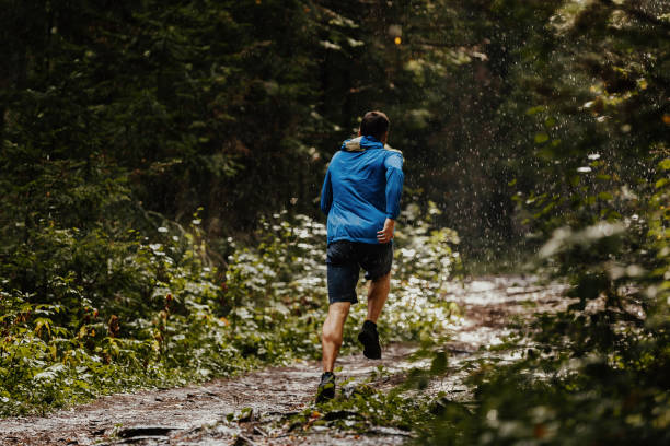 athlète masculin coureur courir le marathon de la forêt sous la pluie - courir sous la pluie photos et images de collection