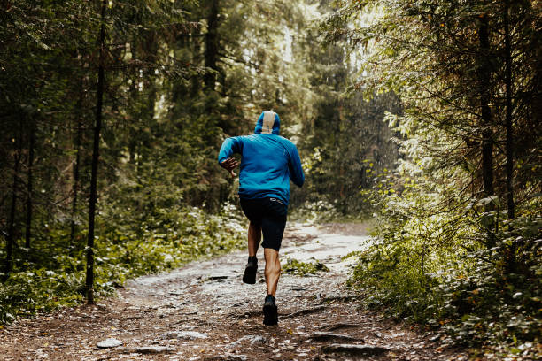 istock back male runner athlete in hood running forest 859978930