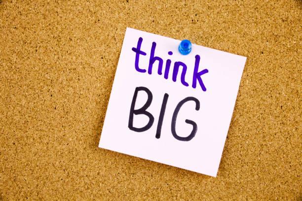 istock A yellow sticky note writing, caption, inscription think big concept words on blackboard in black ext on a sticky note pinned to a cork notice board 859979110