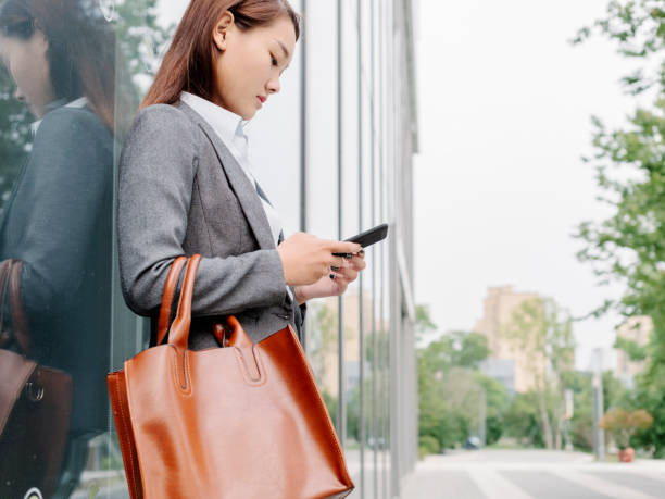 istock business woman leaning on glass wall using smartphone 859980112