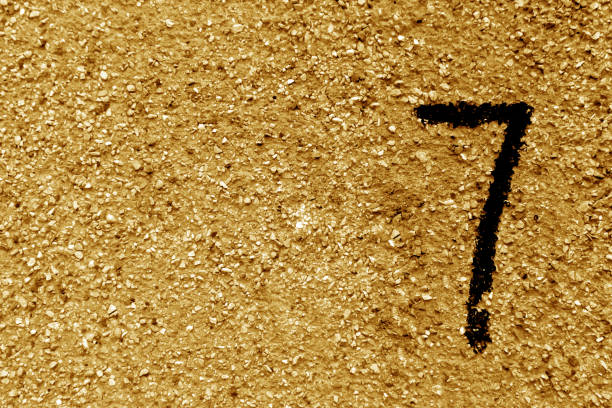 istock Number seven on orange grungy cement wall. 859983192