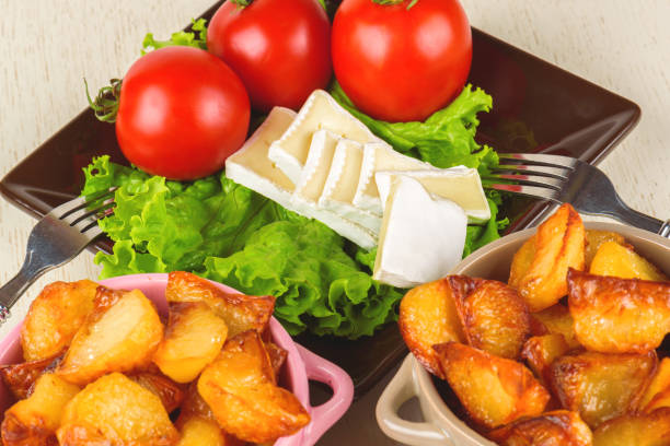 Breakfast from cheese, tomatoes, potatoes and all-over salad on a wooden table closeup.