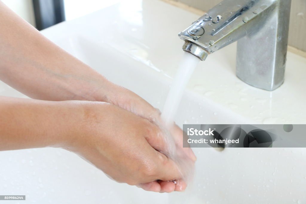 The woman cleaning dirty hands by washing hand with foam soap and water in white sink in bathroom Adult Stock Photo