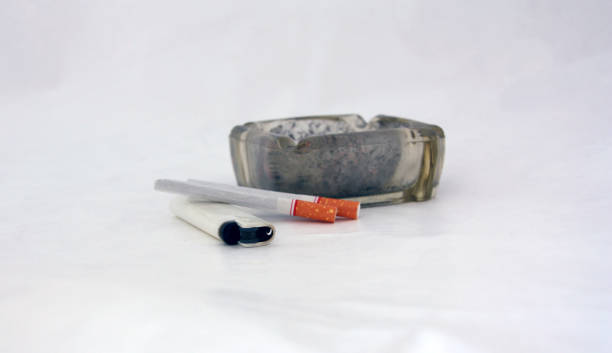 istock White lighter and two cigarettes with Full ashtray of cigarettes, on white background. 859995080