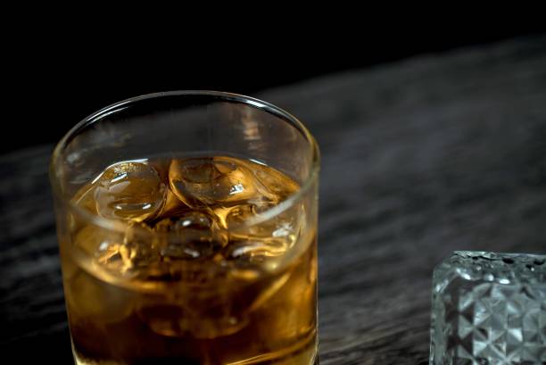 istock Glass of whiskey with ice on black stone table. 860012126