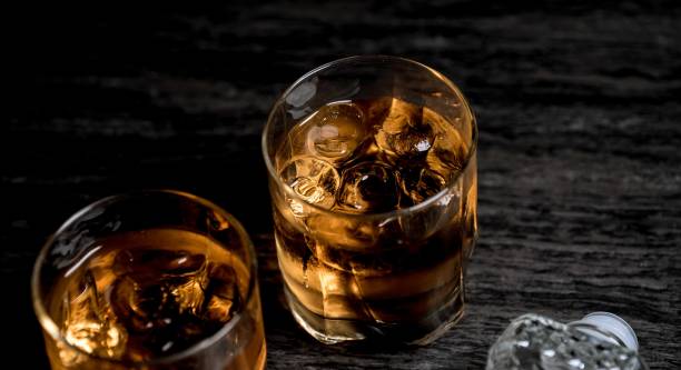 istock Glass of whiskey with ice on black stone table. 860012164