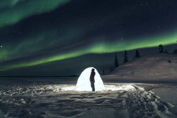 viajero frente a iglú bajo el cielo de aurora - yellowknife fotografías e imágenes de stock