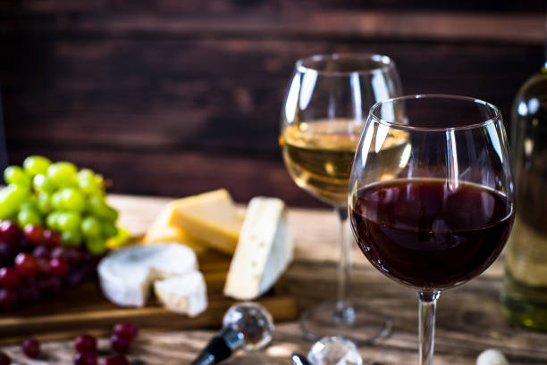 Glass of  wine, cheeses and grapes on brown wooden background stock photo